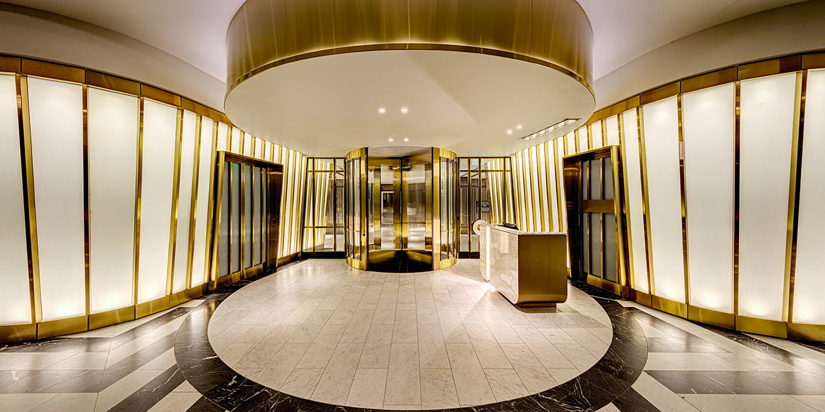 Gold-toned stainless steel entrance lobby with framed doors and a circular reception zone