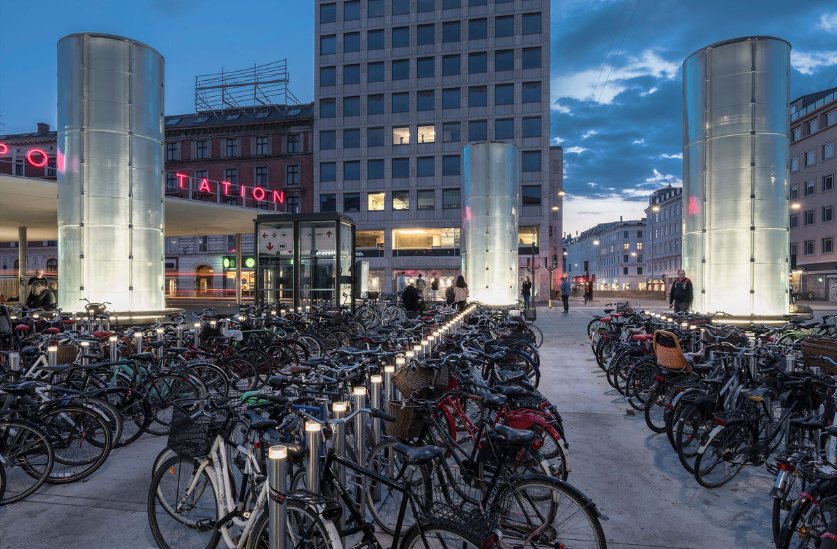 Slender stainless-steel bicycle stands arranged across the Nørreport Station square