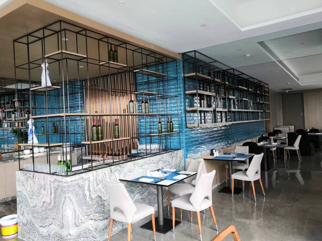 A stainless steel hotel bar counter and wine display shelving serve the Hilton lobby and dining area.