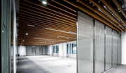 Slim stainless steel room dividers beneath a timber-panelled ceiling