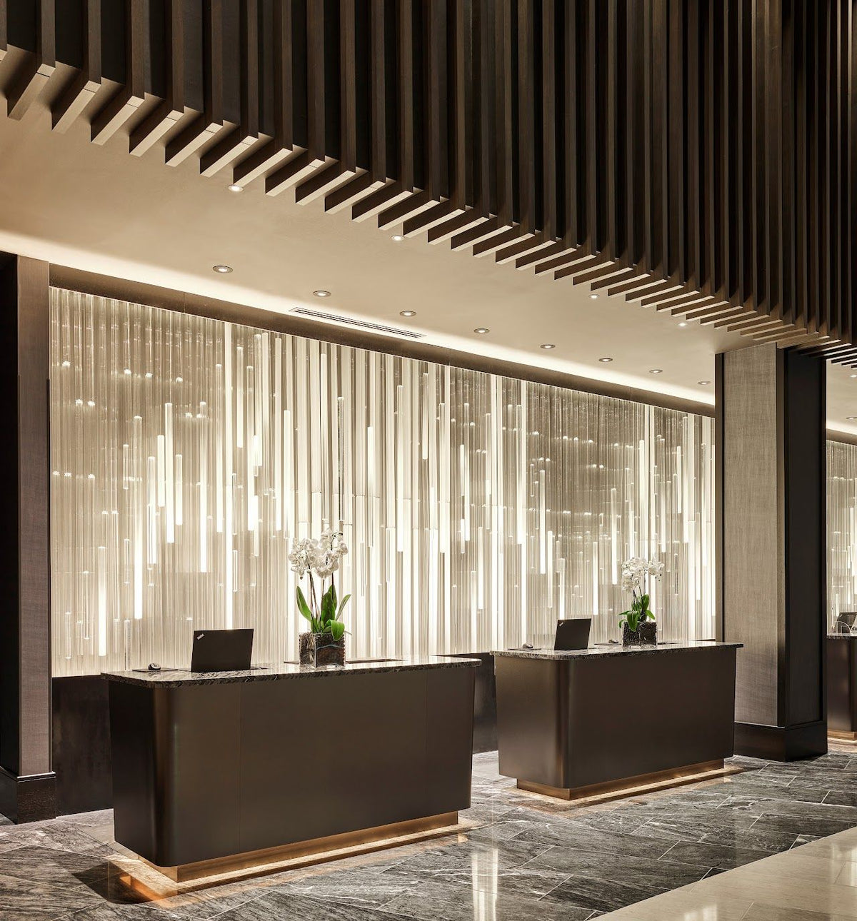 Two dark stainless steel reception desks arranged in a commercial interior
