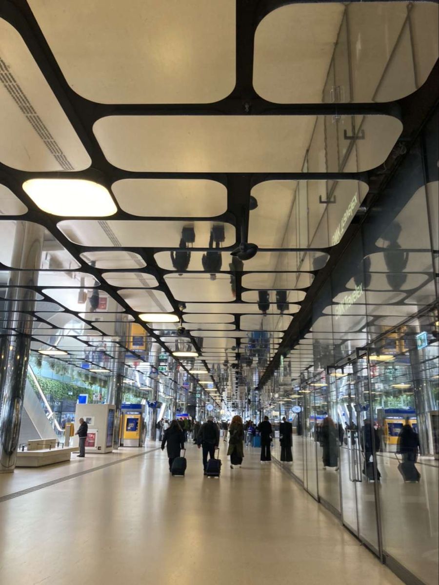 Rounded rectangular mirror ceiling modules above a public passage