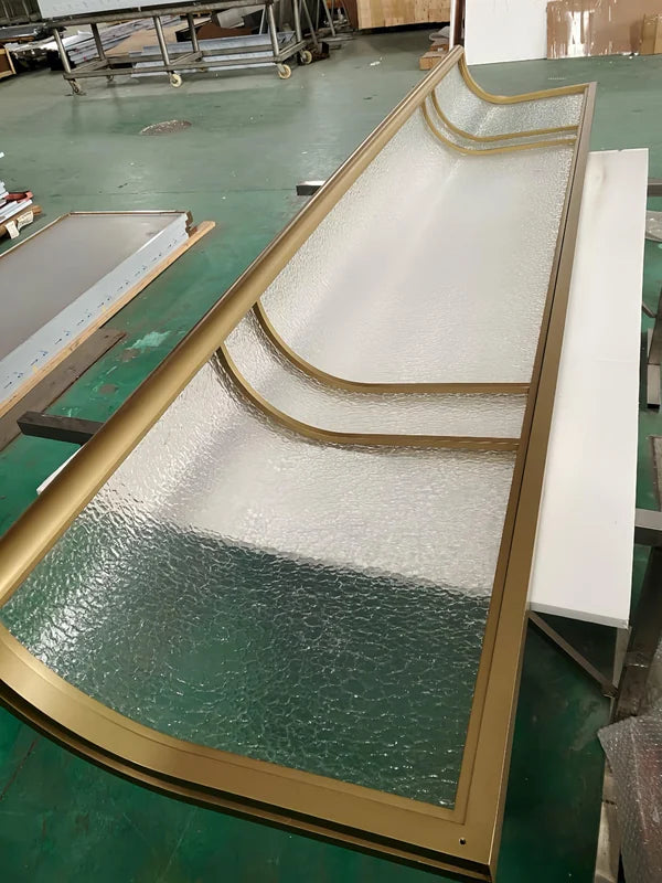Overall workshop view of curved bronze textured glass stainless steel screen