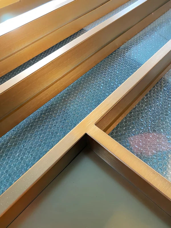 Surface and edge detail of gold linear architectural stainless steel screen frame