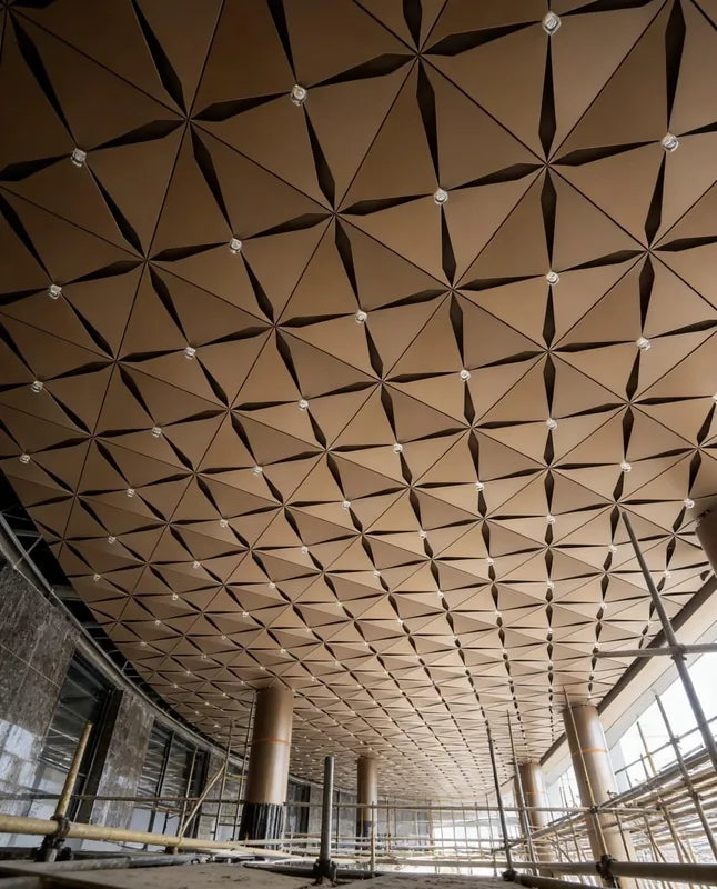 Long view of repeated square bronze aluminum ceiling modules during installation