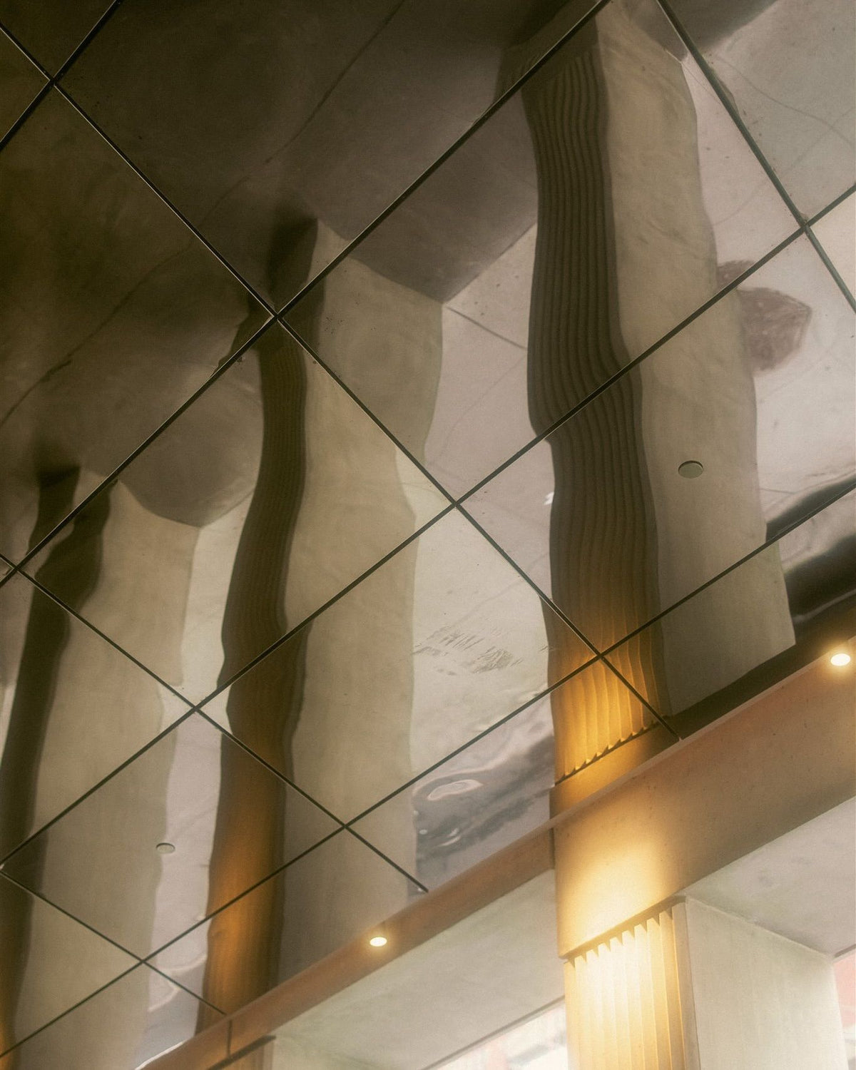 Mirror ceiling panels reflecting tall columns and lights in an interior