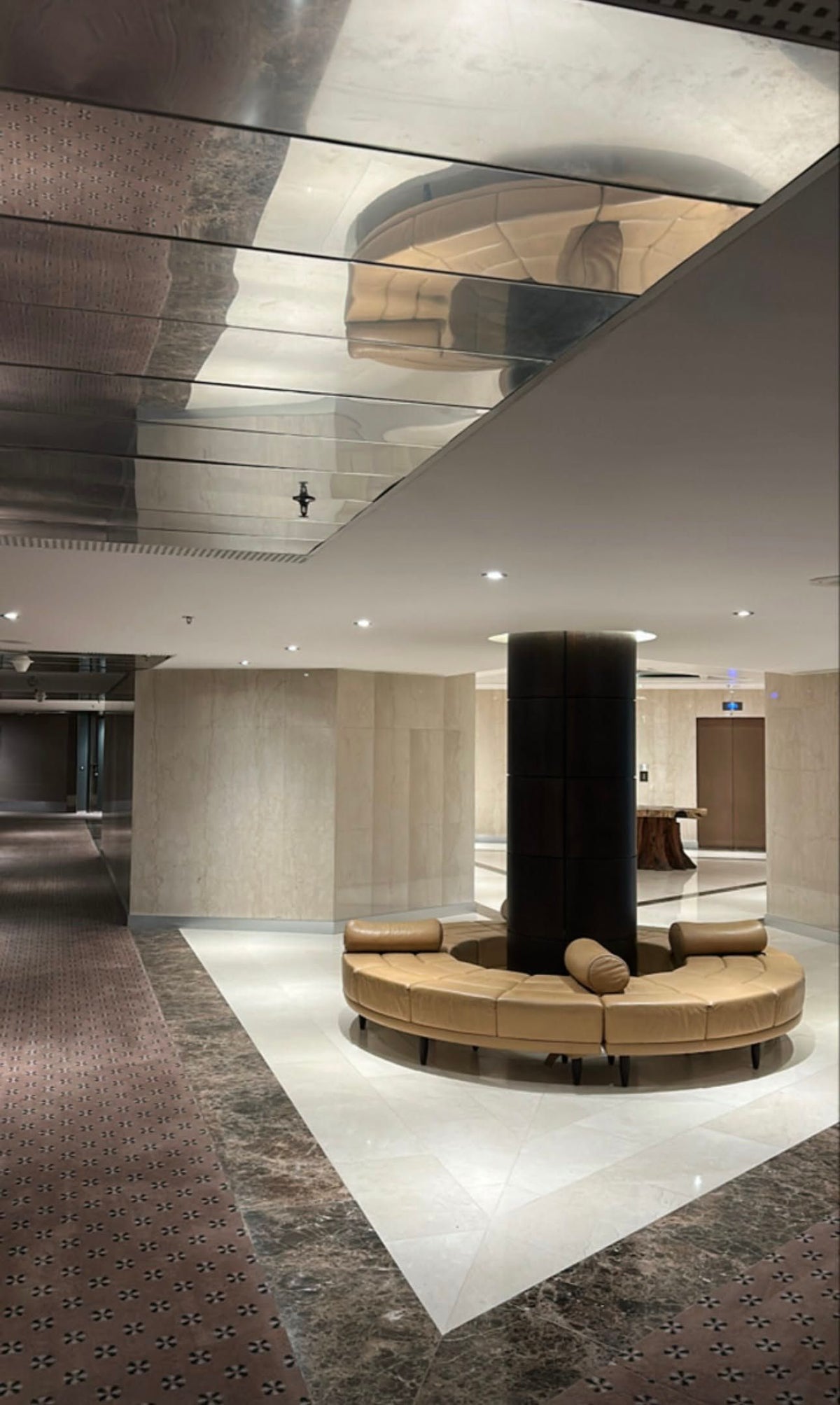 Large reflective ceiling panels above a circular seat in a lobby
