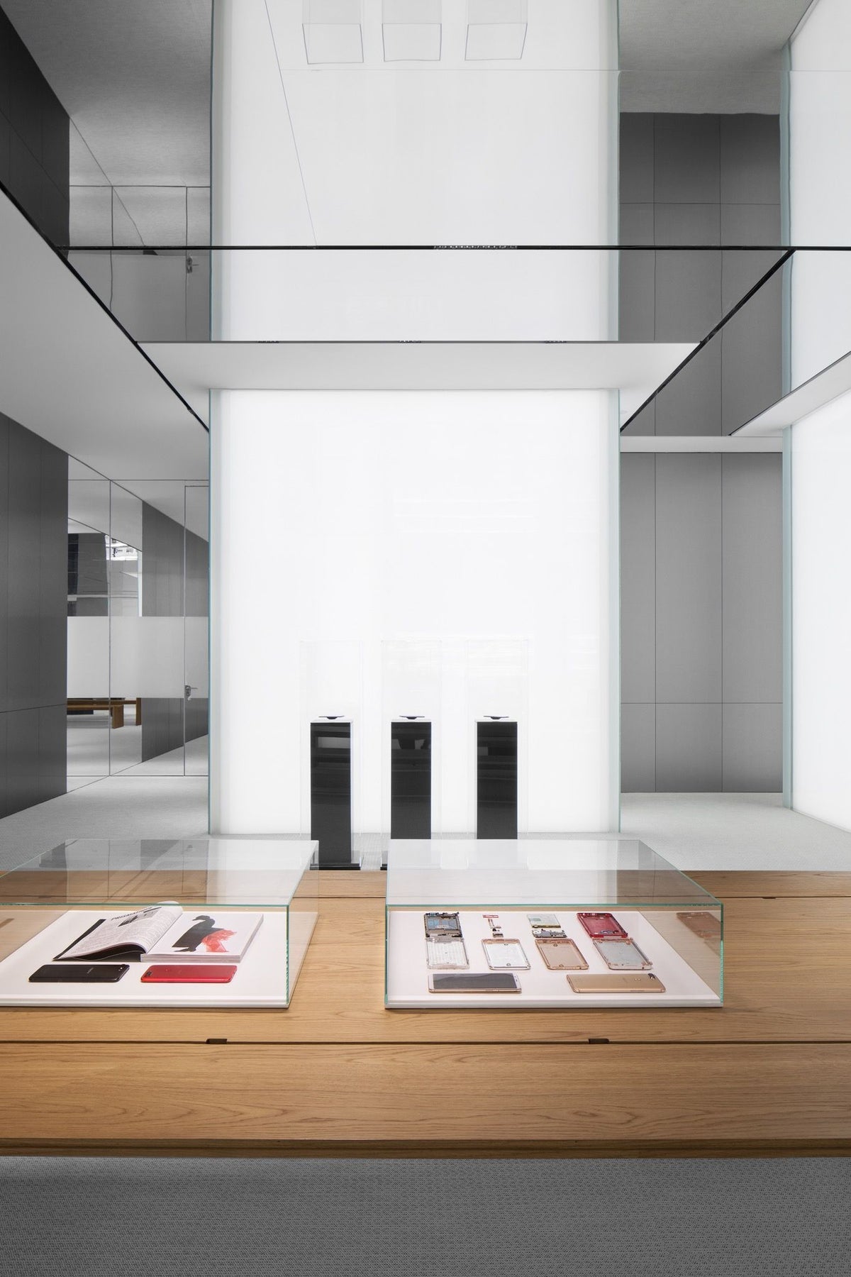 Flat mirrored ceiling panels above white retail display walls and timber table
