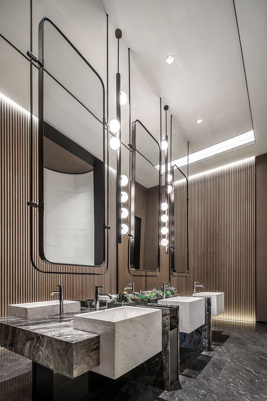Tall dark framed commercial mirror cabinets above a washroom vanity
