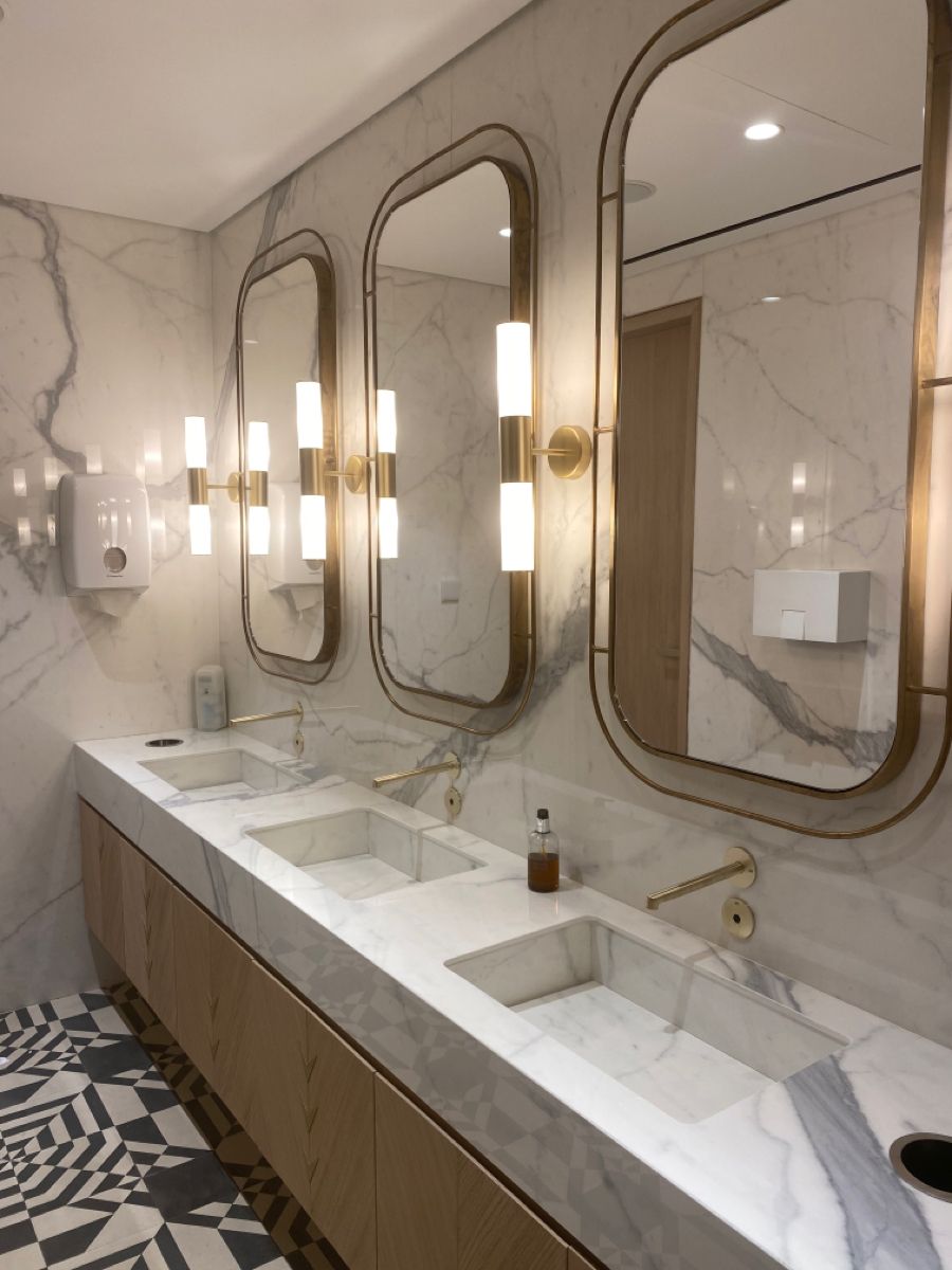 Bronze framed tall mirror cabinets in a marble vanity area