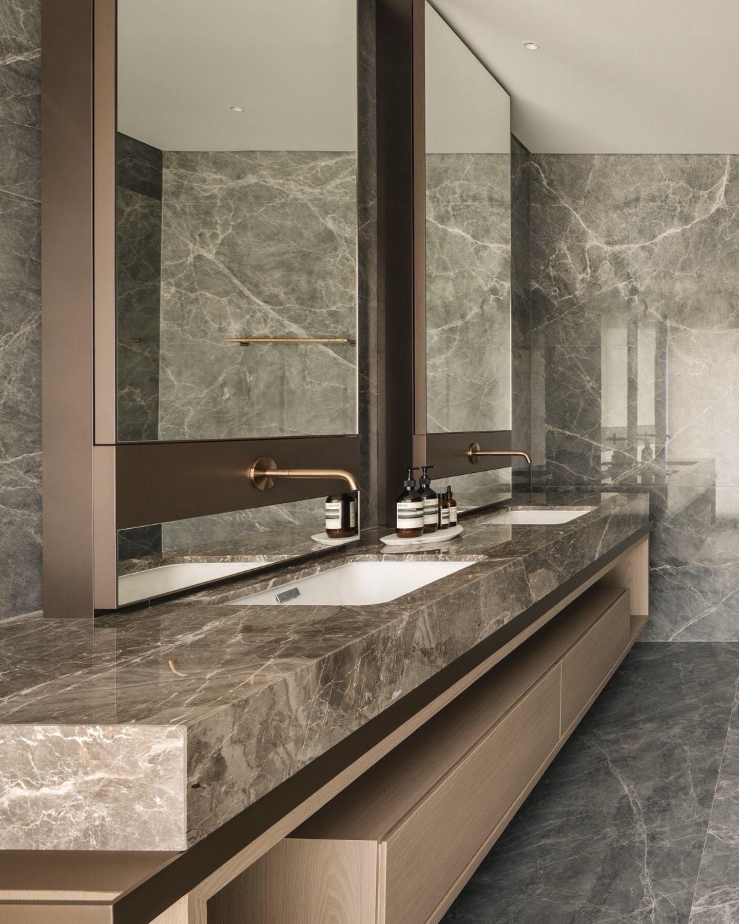 Bronze framed mirror cabinets over a marble double vanity