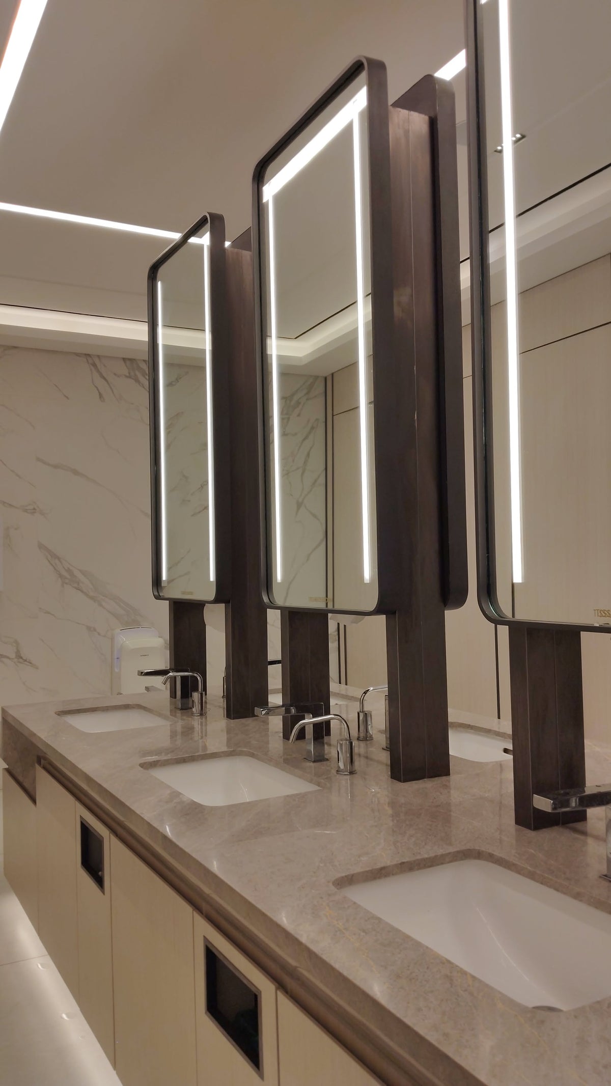 Illuminated bronze mirror cabinet panels over a vanity