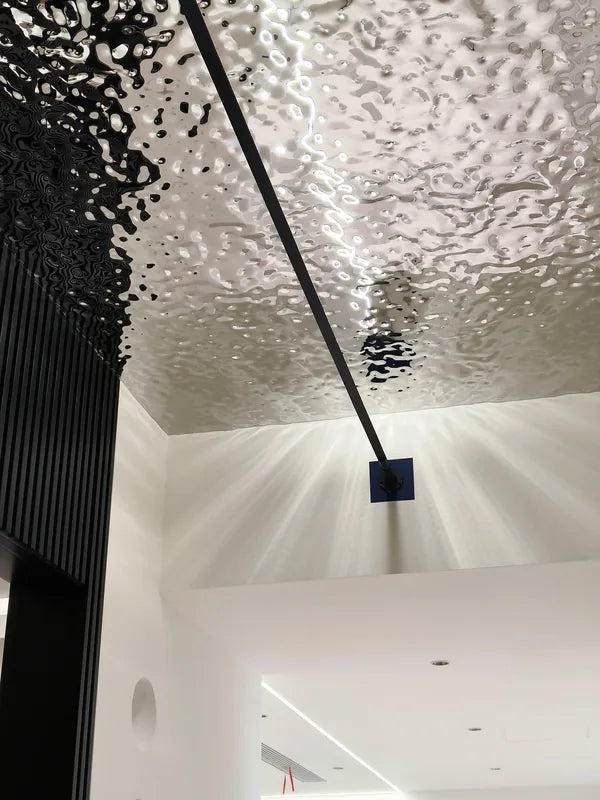 Silver water ripple ceiling with black linear light in white hallway, near view