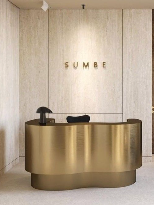 Curved bronze-tone stainless steel reception desk for hotel, clinic and executive office lobbies