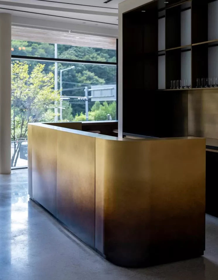 Curved bronze-tone stainless steel reception desk for hotel, clinic and executive office lobbies