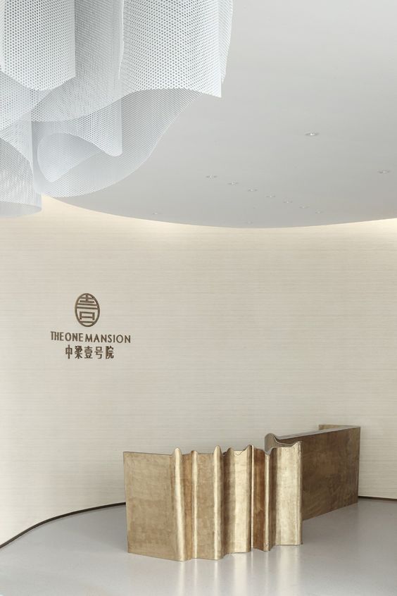 Sculptural folded bronze-finish stainless steel reception desk for premium commercial interiors