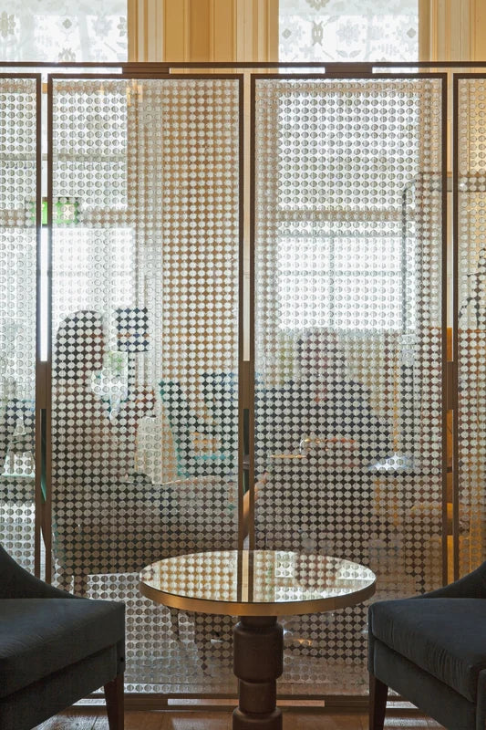 Bronze perforated metal screen partition enclosing a dining area