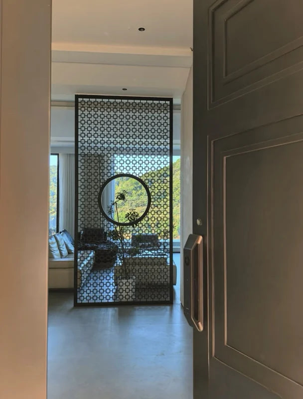 Dark stainless steel geometric screen partition viewed through an interior doorway