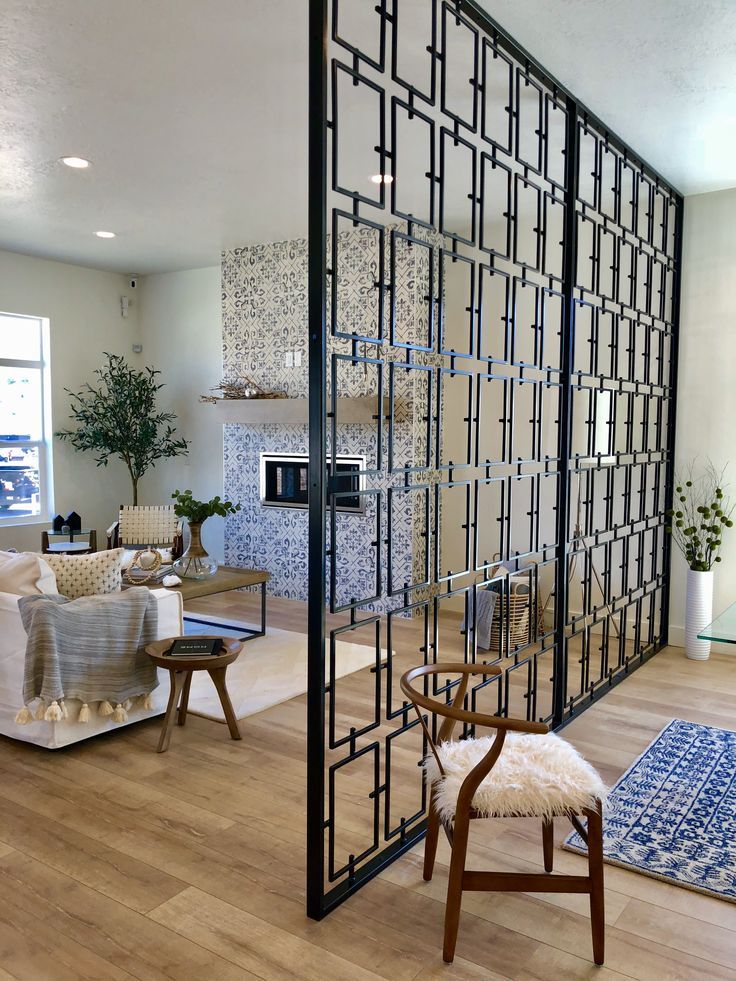 Black geometric stainless steel screen partition with a repeating angular pattern in a living room.