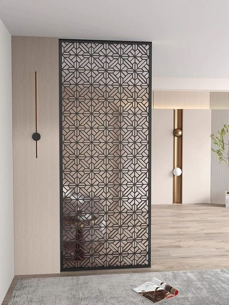Dark stainless steel screen panel with a repeating angular geometric pattern in a living room.