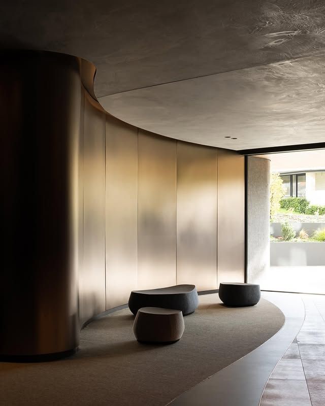 Bronze-toned stainless steel panels following a curved entrance wall.