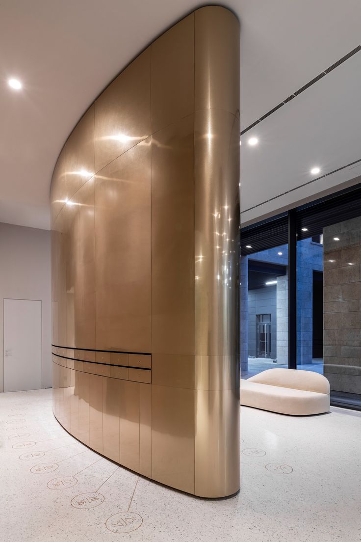 Bronze-toned stainless steel wall cladding wrapping a curved architectural wall.