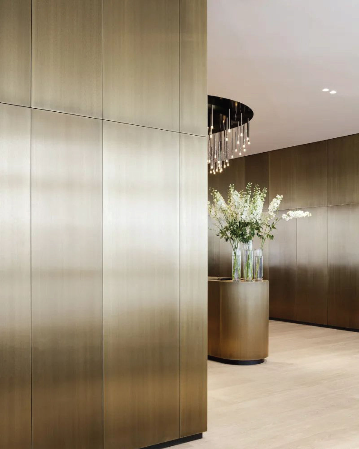 Warm bronze-toned stainless steel wall panels wrapping a curved lobby wall.