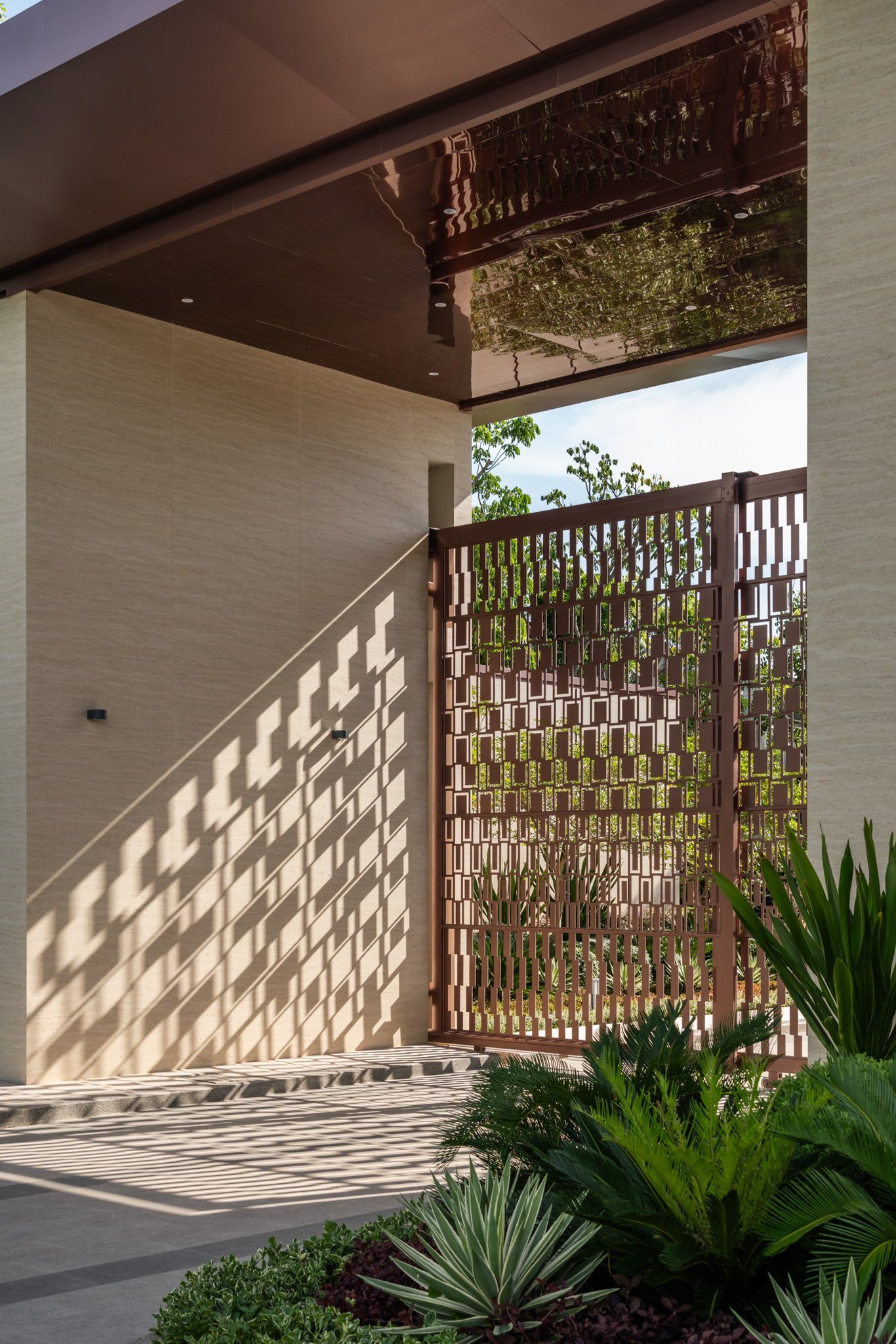 Bronze-toned stainless steel screen wall with a repeating rectangular pattern at an entrance.