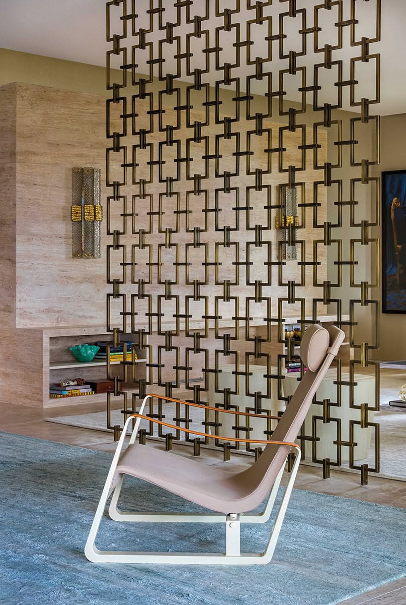 Bronze-toned stainless steel screen divider with an open rectangular link pattern in a living area.