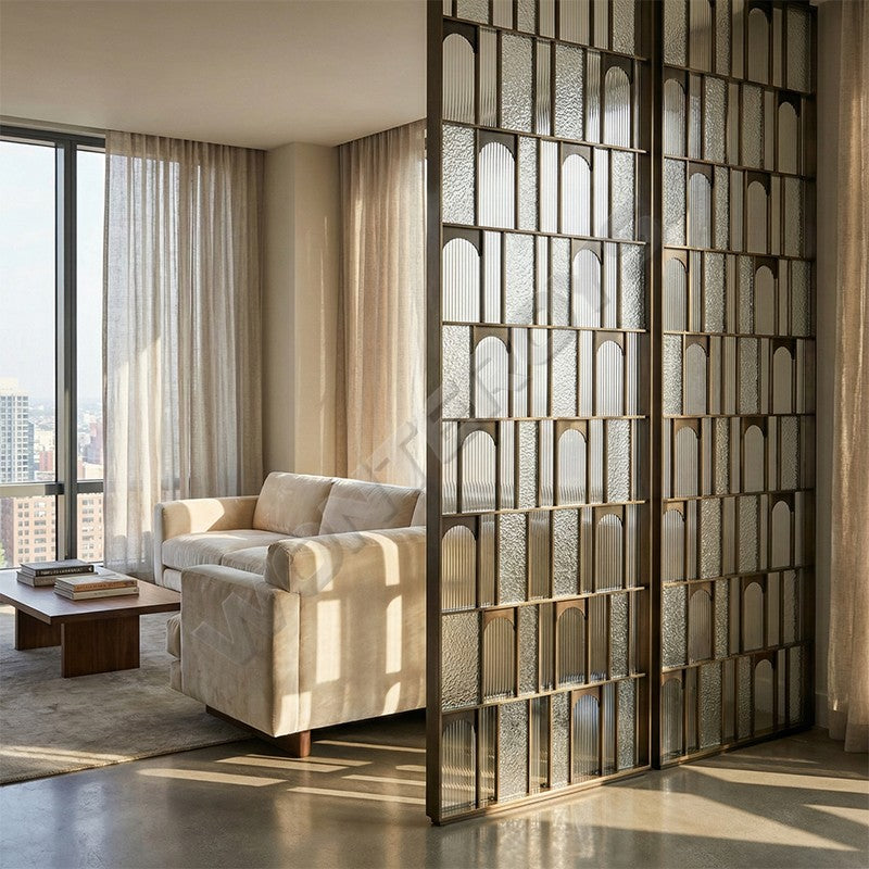 Bronze-toned stainless steel screen with arched textured panels dividing a living room.