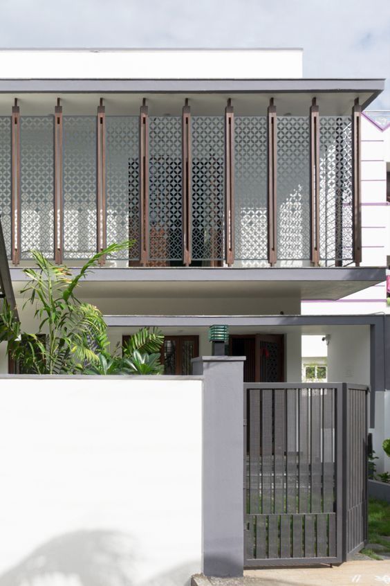 Bronze-toned stainless steel screen panels with a repeating geometric pattern across a residential facade.