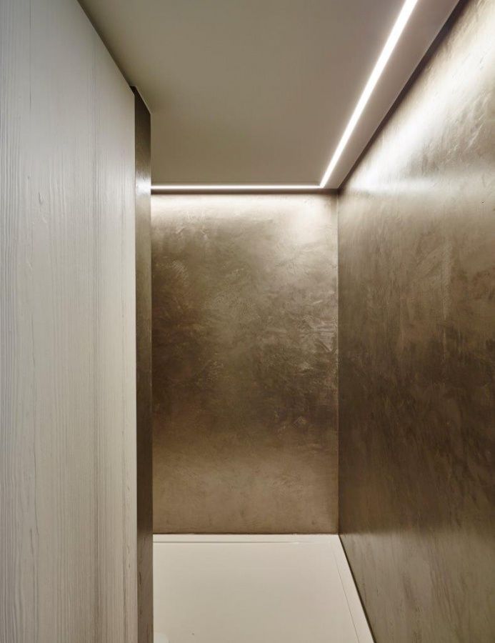 Bronze-toned textured stainless steel wall cladding in a narrow interior passage.