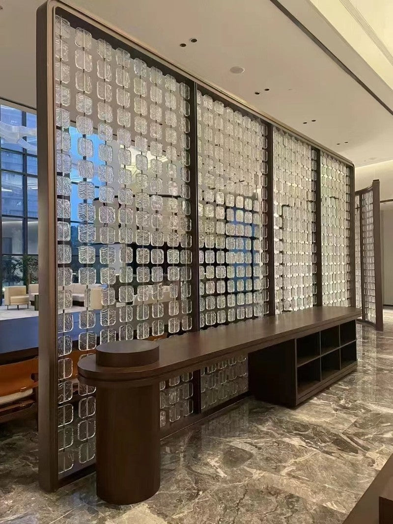 Dark framed stainless steel screen with textured translucent panels dividing a restaurant interior.