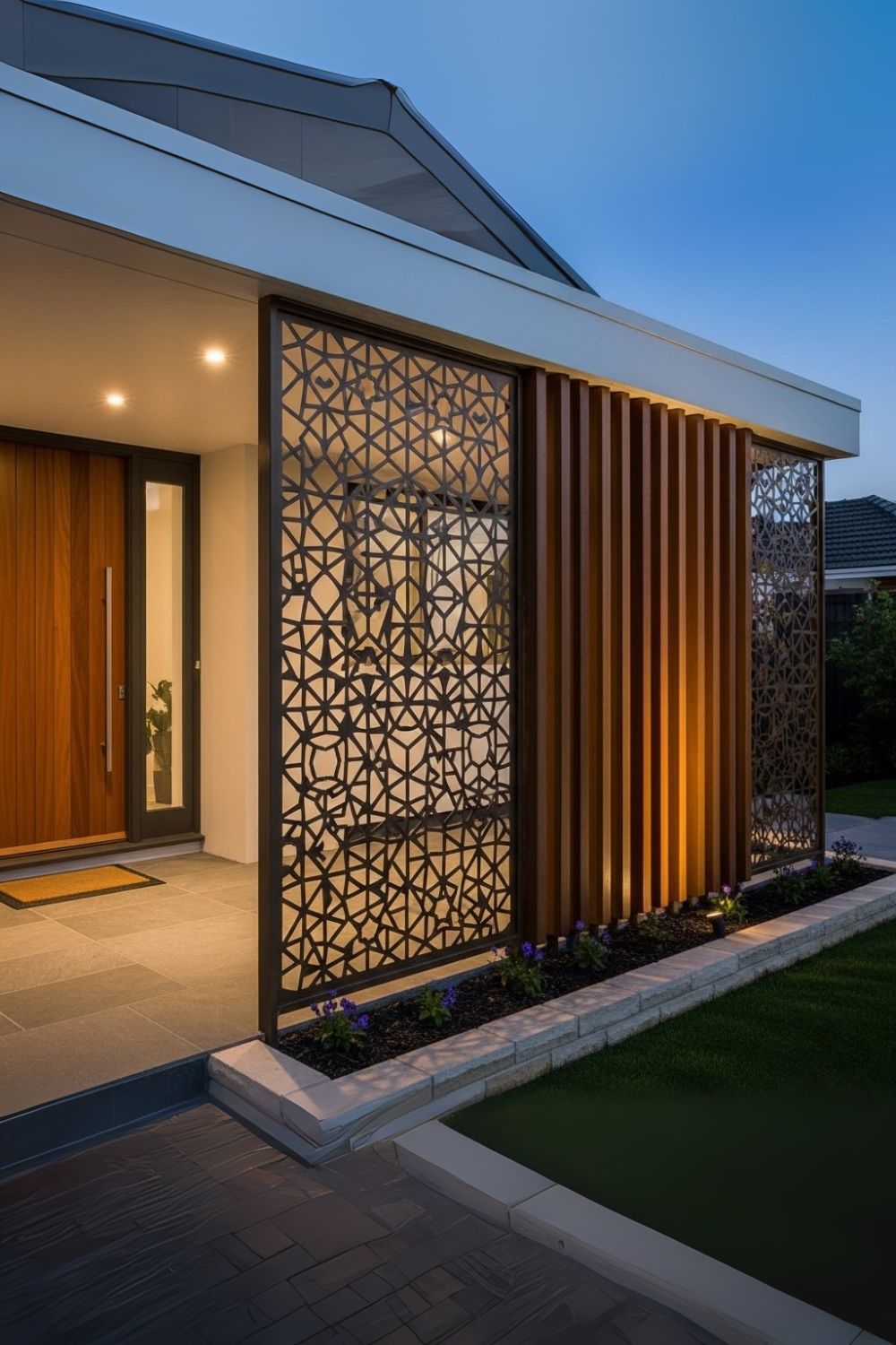 Dark perforated stainless steel screen wall with an irregular geometric pattern beside an entrance.