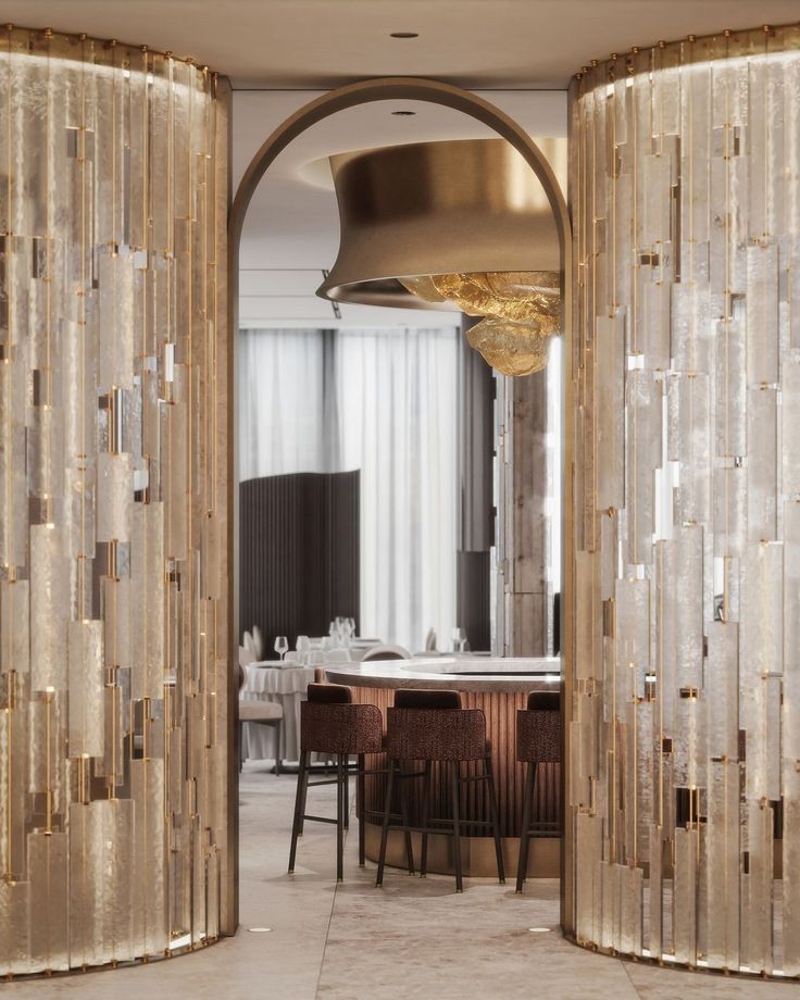 Gold-toned stainless steel screen with translucent vertical panels framing a dining area.