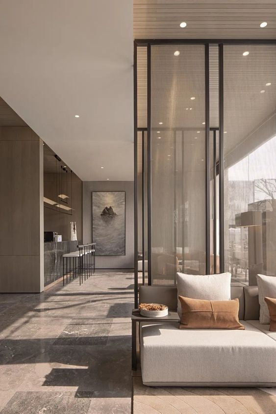 Silver-toned stainless steel mesh screen dividing a modern lounge and living area.
