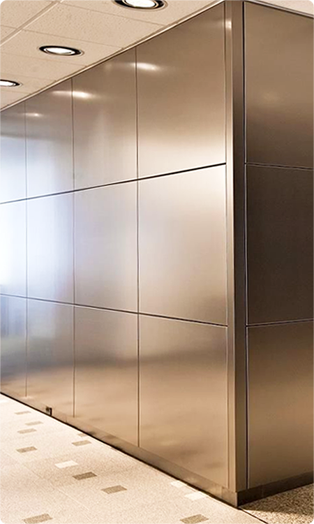 Silver metallic stainless steel wall cladding with regular joints along an interior corridor.