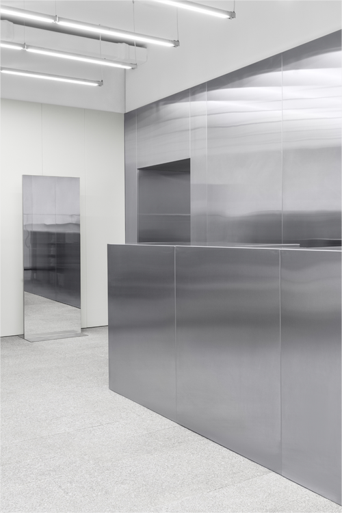 Silver smooth stainless steel wall cladding across a modern retail interior.
