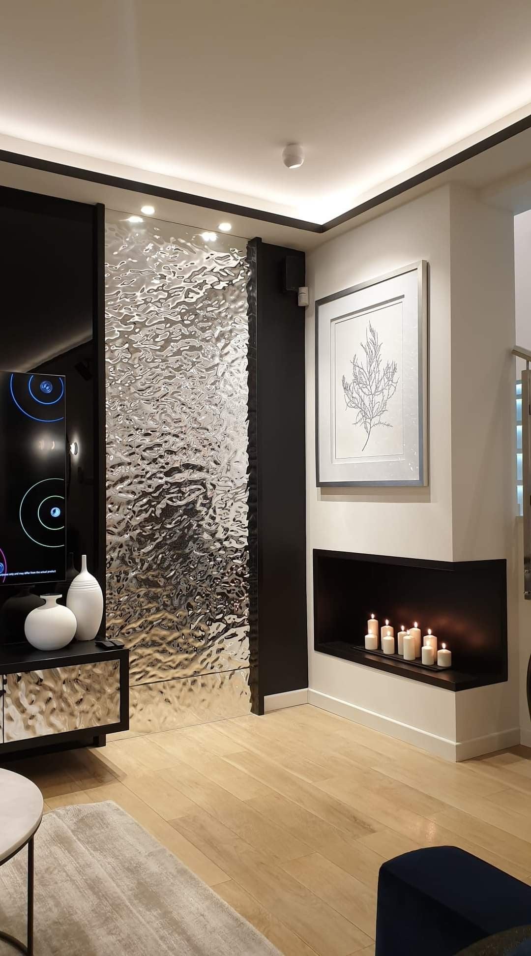 Silver water ripple stainless steel wall panel beside a living room fireplace.